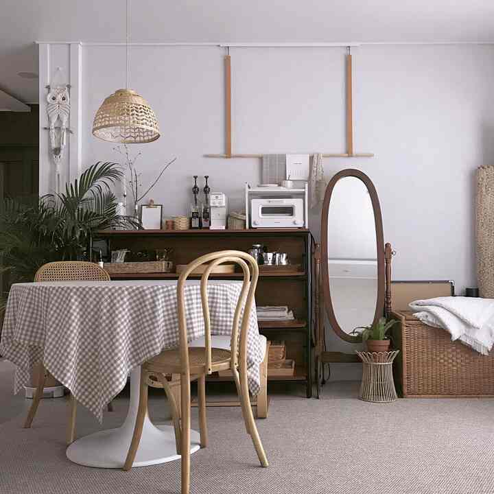 Natural toned living room home cafe space featuring a round dining table, rattan chairs, and a full-length mirror with cozy decor