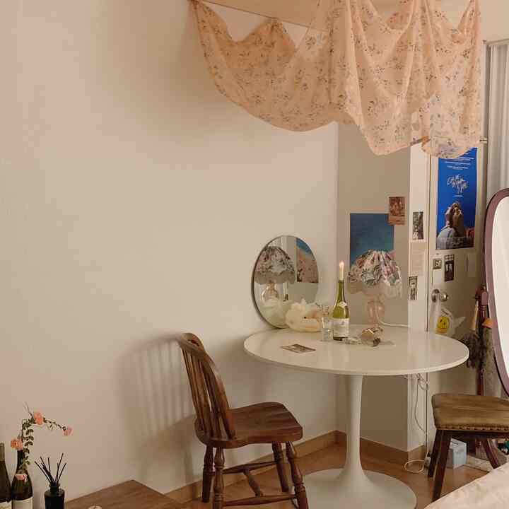 アイボリーとブラウンの色調の円形の部屋、丸テーブルと木製の椅子がかわいらしいヴィンテージ感を演出する空間