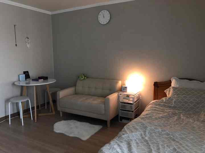 ベージュのトーンのワンルーム寝室、ベージュのソファとベッドが配置された落ち着いた空間