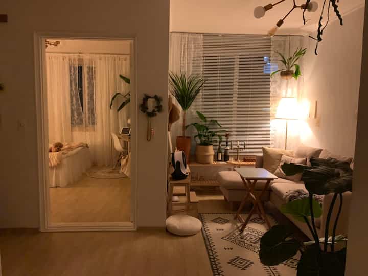 Warm natural wood tones and beige sofa in living room with cozy bedroom visible, creating serene nighttime atmosphere