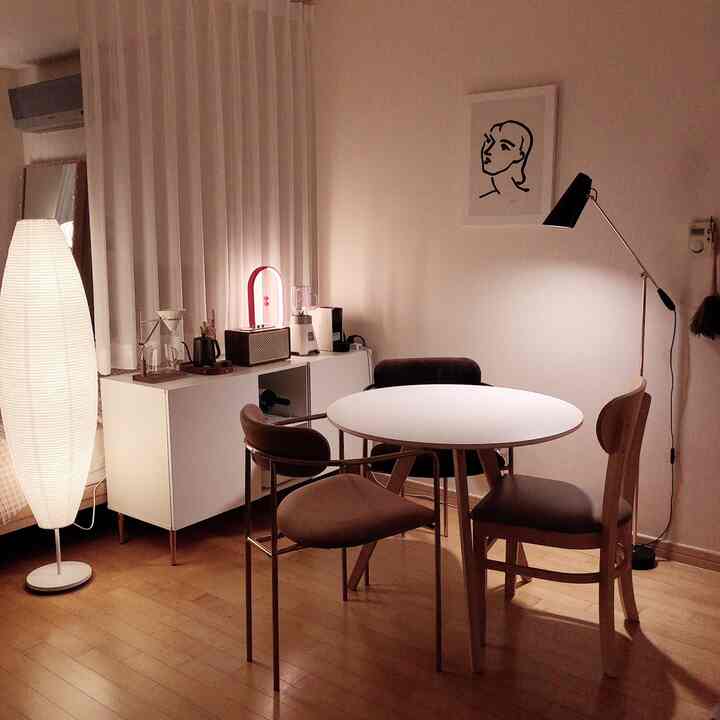 ホワイトとナチュラルな木調のワンルームダイニングスペース、円形のテーブルとシンプルな照明が配された温かみのある雰囲気のインテリア