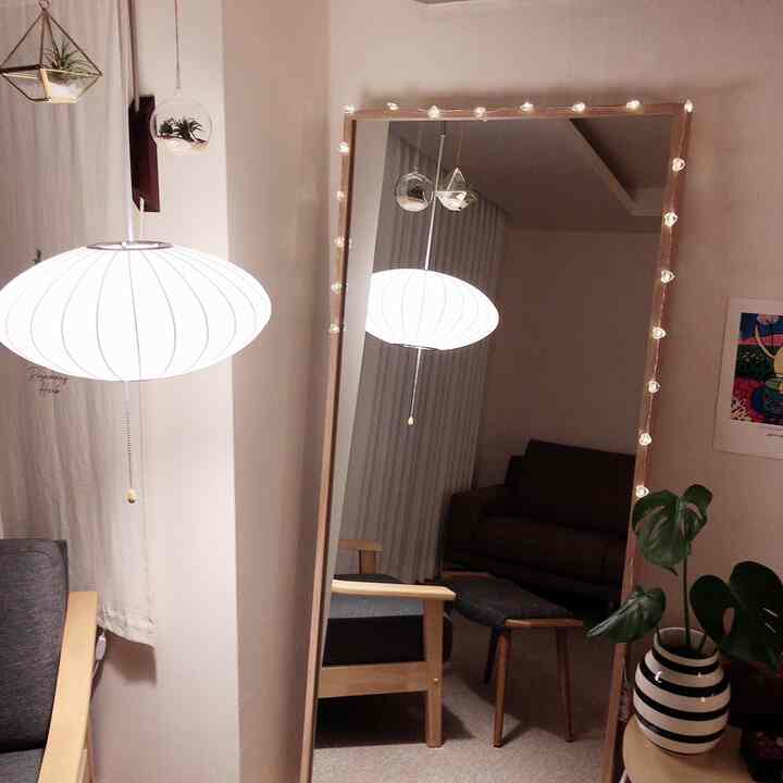 Natural-toned studio living room featuring a photo zone opposite the sofa with a full-length mirror and charming lighting accents