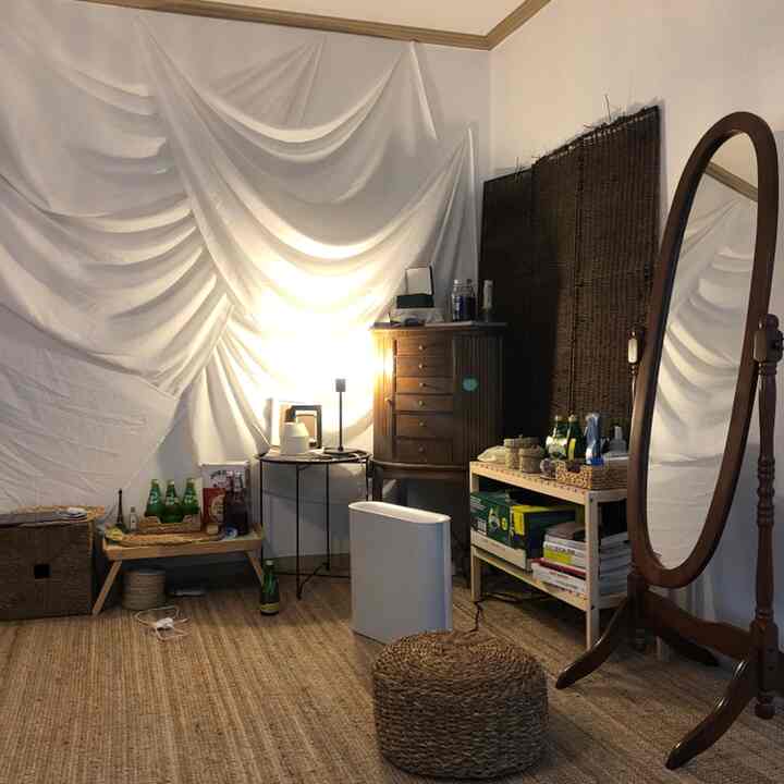 Natural-toned vintage living space featuring rattan objects, large full-length mirror, and various storage shelves creating a cozy atmosphere