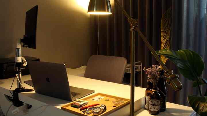 Warmly lit home office space featuring a white desk, office chair, laptop, and task lamp creating a cozy workspace atmosphere
