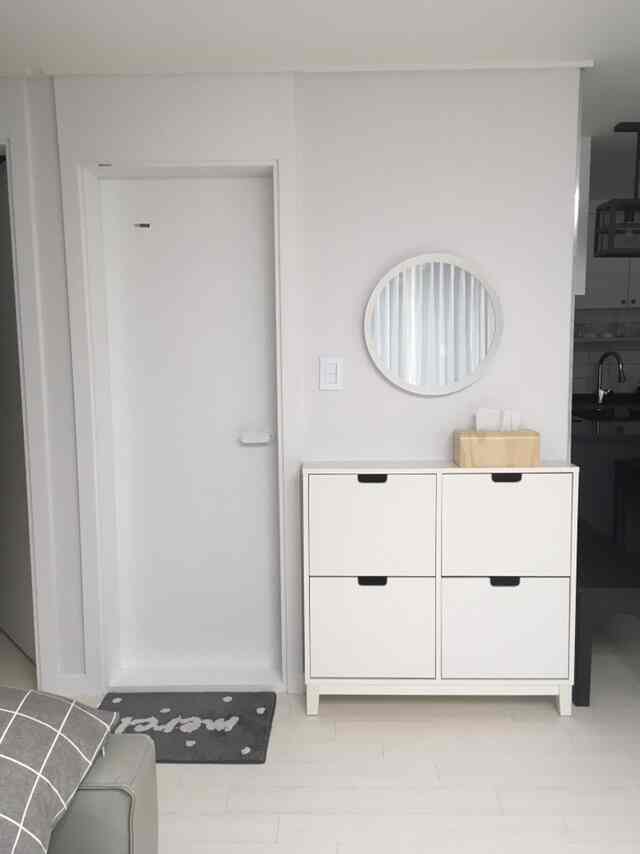 White-toned entrance featuring a neat shoe cabinet and round mirror with a modern atmosphere