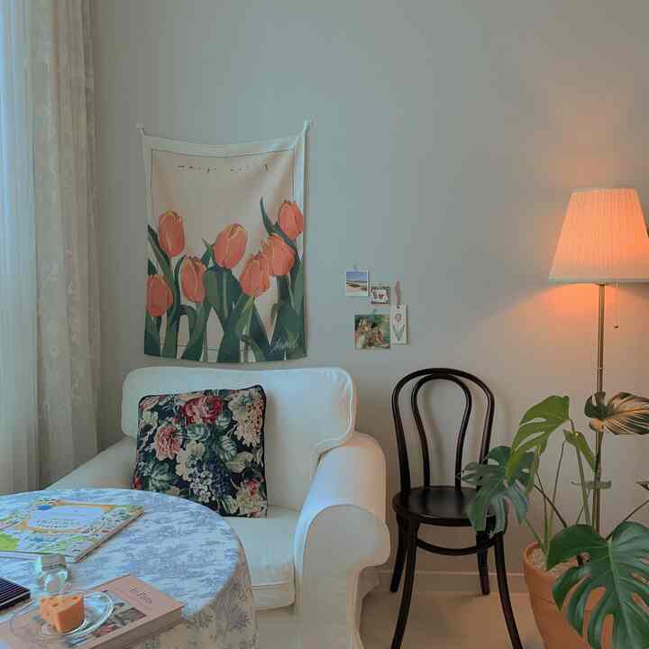 ホワイトとベージュのトーンのリビングの一角、ヴィンテージスタイルのソファとフロアランプ、モンステラの植物が配置された雰囲気のある空間