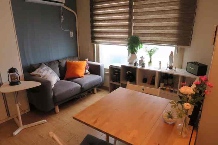 Gray and wood tone living room approximately 6 tatami size, featuring a gray sofa, wooden dining table, shelving, and cushions in a natural modern style