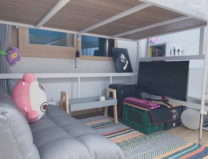 Gray and wood-tone compact living room featuring a gaming monitor and keyboard setup in a minimal home office space