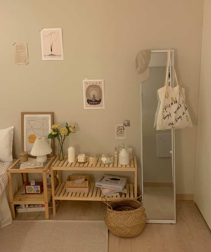 Beige-toned walls and natural wood shelves with a full-length mirror in a cozy living room space