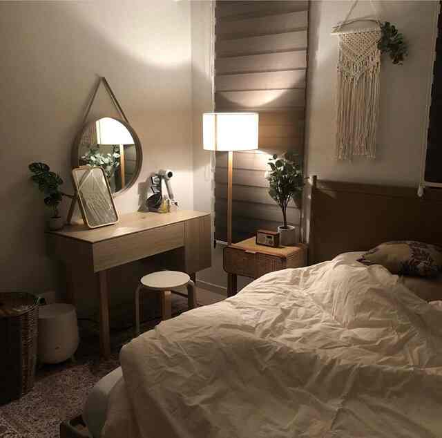 暖かみのある木目調と柔らかな照明が調和した居心地の良い寝室、マクラメ飾りと植物が自然な雰囲気を演出