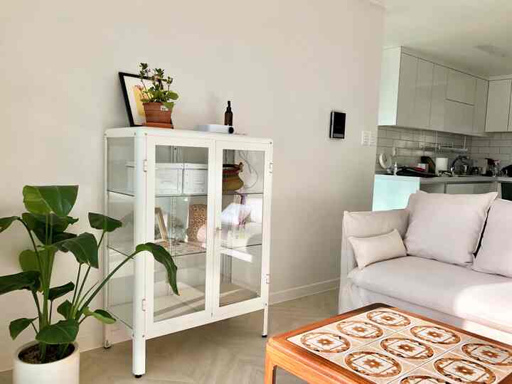 White-toned living room featuring a white glass cabinet and light-colored sofa with a clean and cozy atmosphere