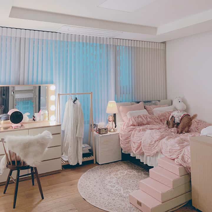 Pink and wood tone bedroom featuring pet-friendly cozy setup with functional storage and soft lighting