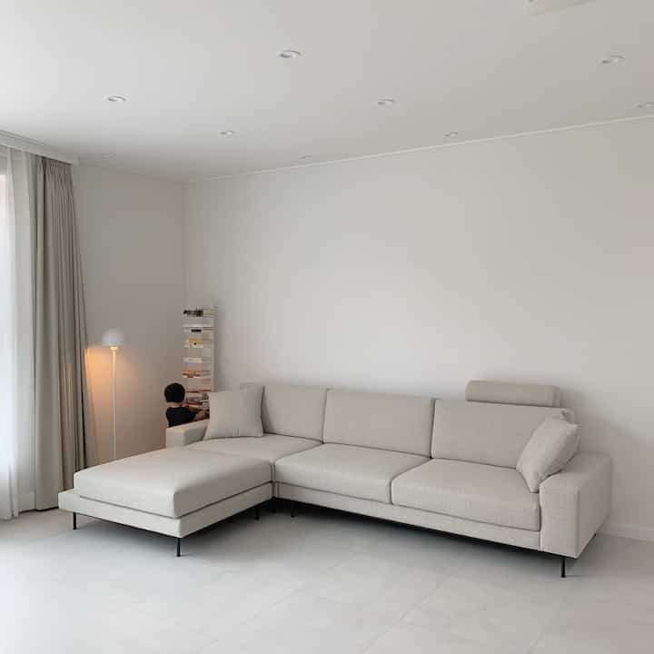 子供と暮らすベージュ色調のシンプルでナチュラルなリビング、モダンなソファと棚が配置された印象的な空間