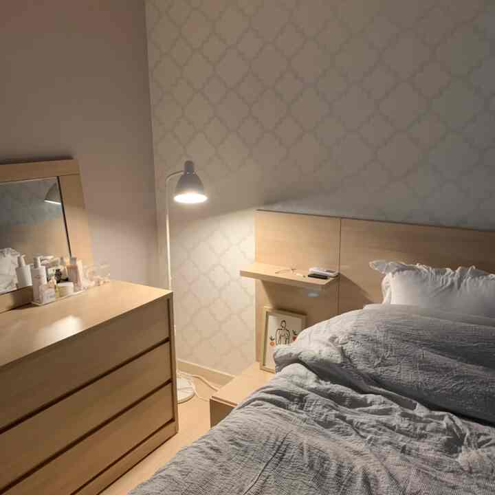 Natural-toned bedroom featuring wooden bed and vanity in a cozy, simple space