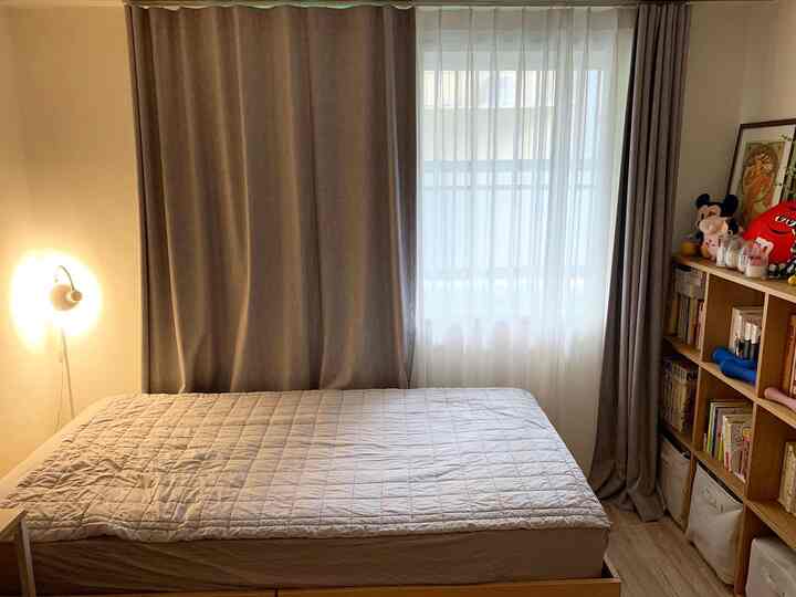 Gray and white toned bedroom featuring blackout and chiffon curtains over the window, with a storage bed and bookshelf arranged for a cozy feel