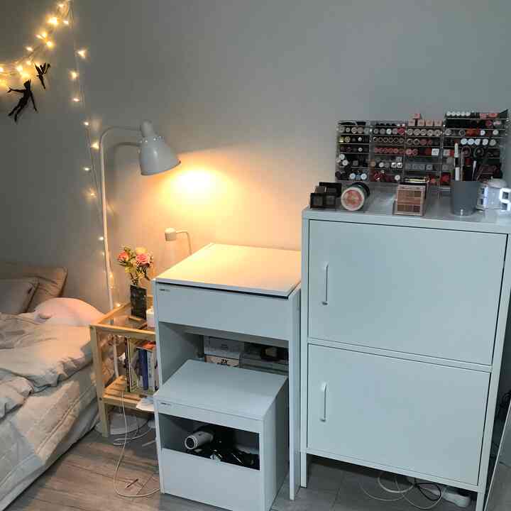 Compact bedroom in white and natural tones featuring vanity and storage cabinets with cozy lighting