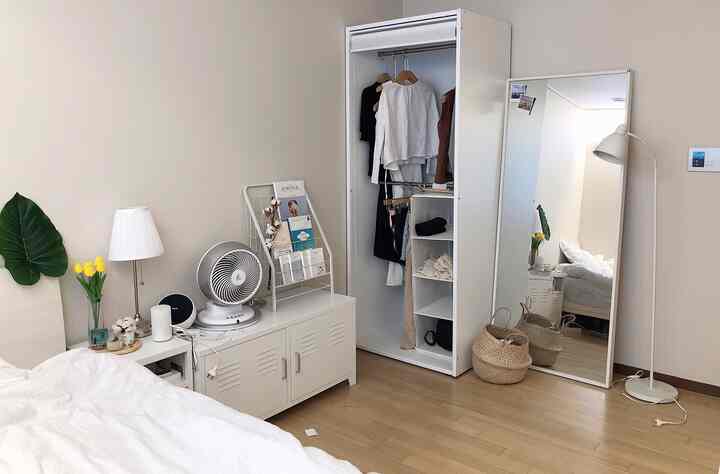 A cozy bedroom featuring white and wood tones, neat storage furniture, and efficient use of space