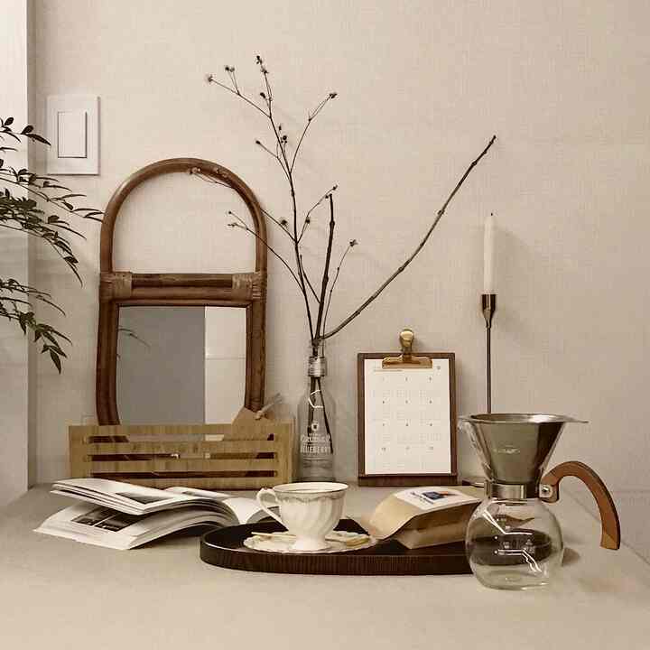 ベージュの背景にブラウンの木製アクセントが調和したおうちカフェ、コーヒードリップセットとカップが配置された雰囲気のある空間