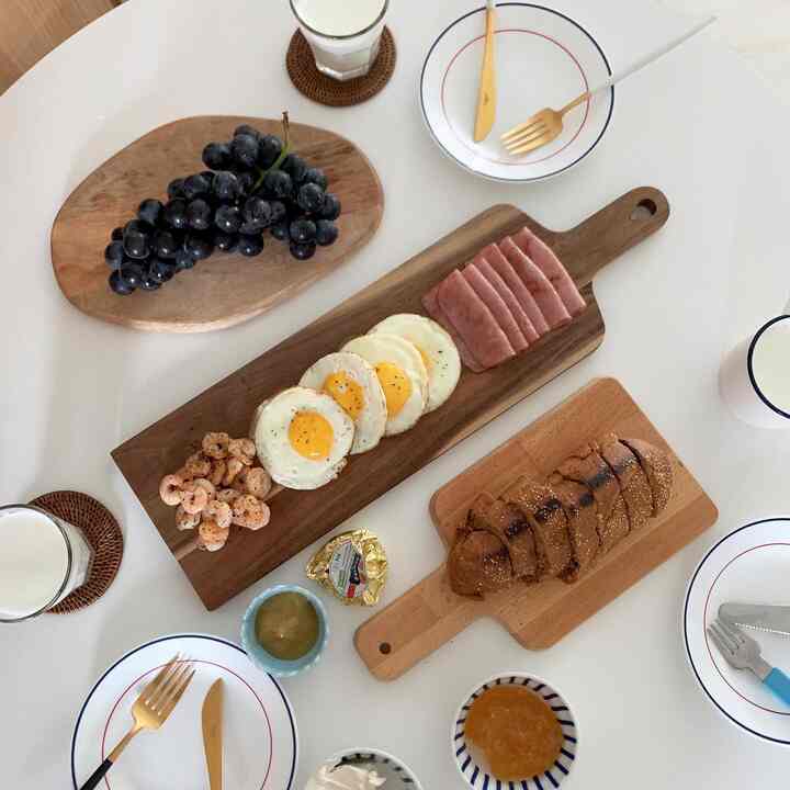 White table featuring wood tone cutting boards with breakfast items in a clean kitchen home cafe setting
