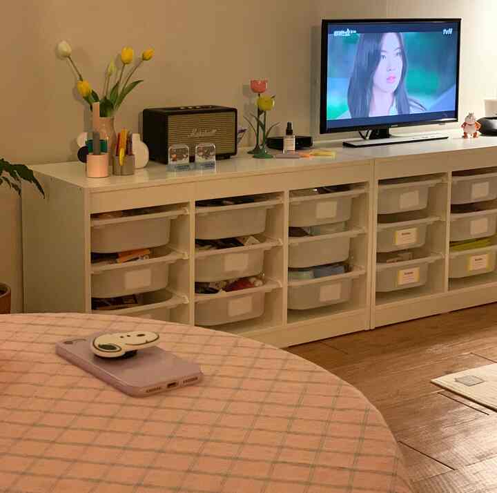 White and brown toned living room featuring TV stand with storage bins, decorated with vases and small ornaments creating warm atmosphere