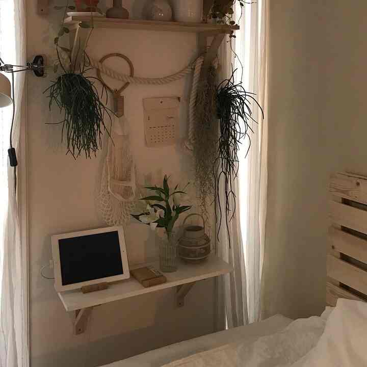 白を基調とした寝室、木製ベッドと棚に植物や小物が配置された雰囲気のあるナチュラルインテリア