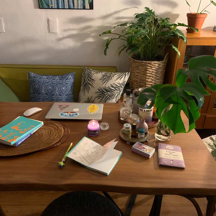 Natural-tone living room with brown wood dining table and cushions, adorned with various plants creating a cozy atmosphere