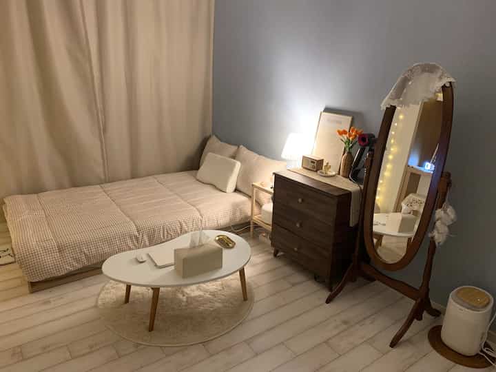 Soft beige and pastel blue bedroom space featuring nightstand, dresser, full-length mirror, and coffee table in cozy natural modern style