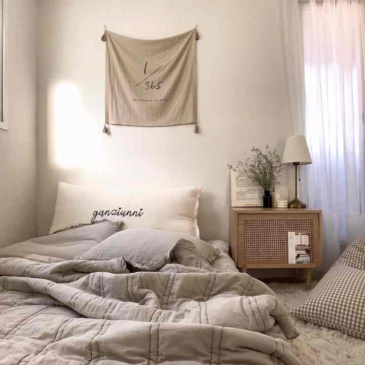 Beige-toned bedroom featuring large cushions and a floor lamp, showcasing a natural and cozy atmosphere