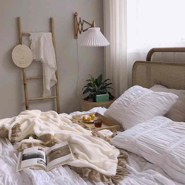Ivory and wood tone natural bedroom featuring a cane bed frame and cozy throw blanket with warm autumn ambiance