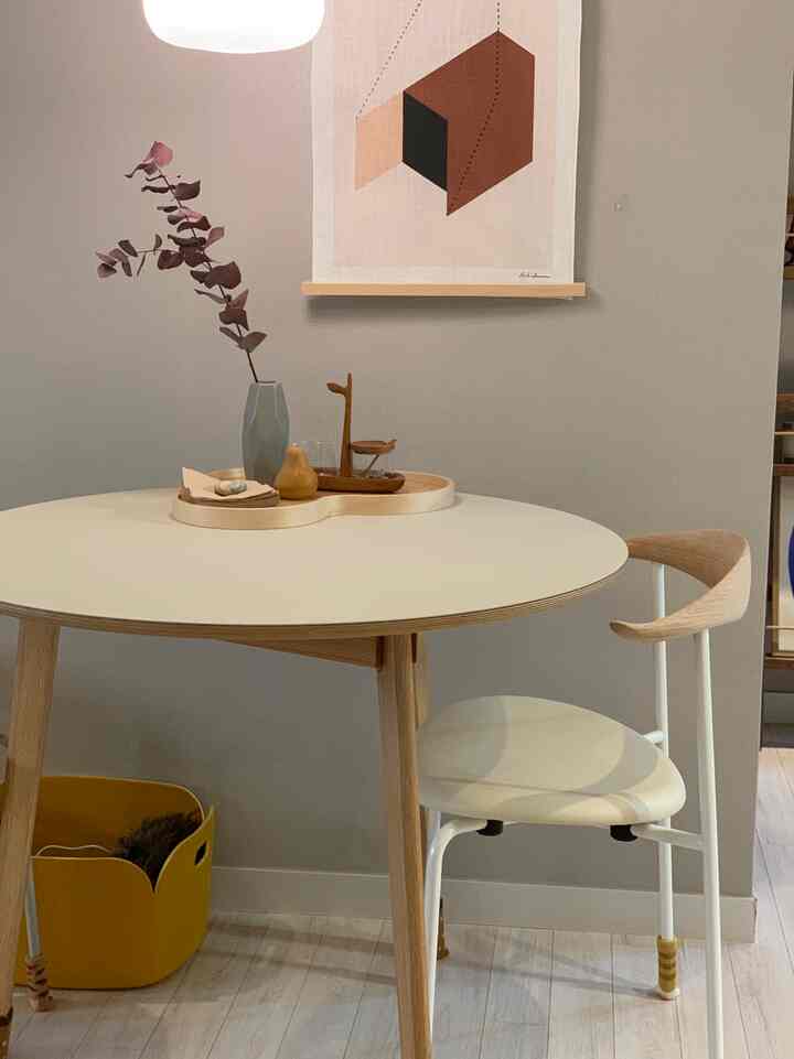 Neutral and wood tone dining room featuring a round dining table and wooden armchair in a simple setting