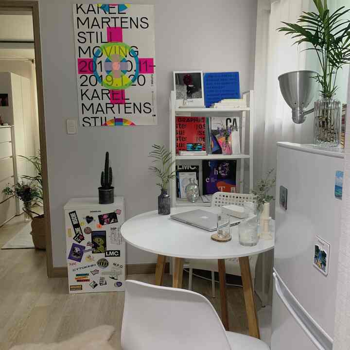White and wood tone studio space featuring a round table, chairs, bookshelf, and plants with a cozy vibe