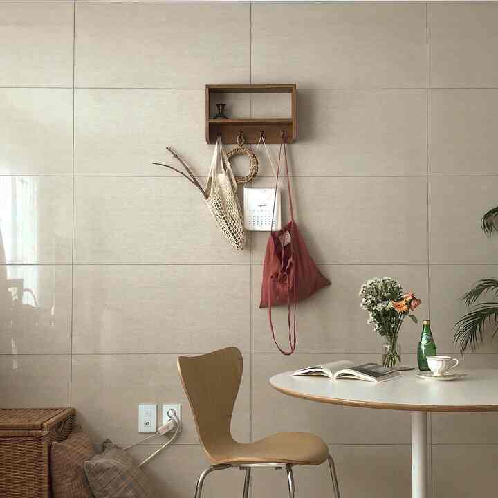 Beige tiled wall natural dining room with wood tone dining chair, featuring vase and coffee cup on table