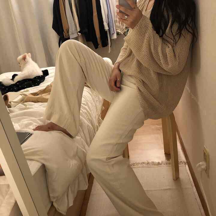 Cozy photo zone in warm beige and white tones featuring a full-length mirror, clothing, and a small dog