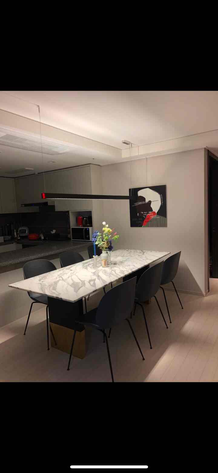 White and navy toned dining room featuring marble dining table, navy chairs, modern art, and pendant light in a clean setting