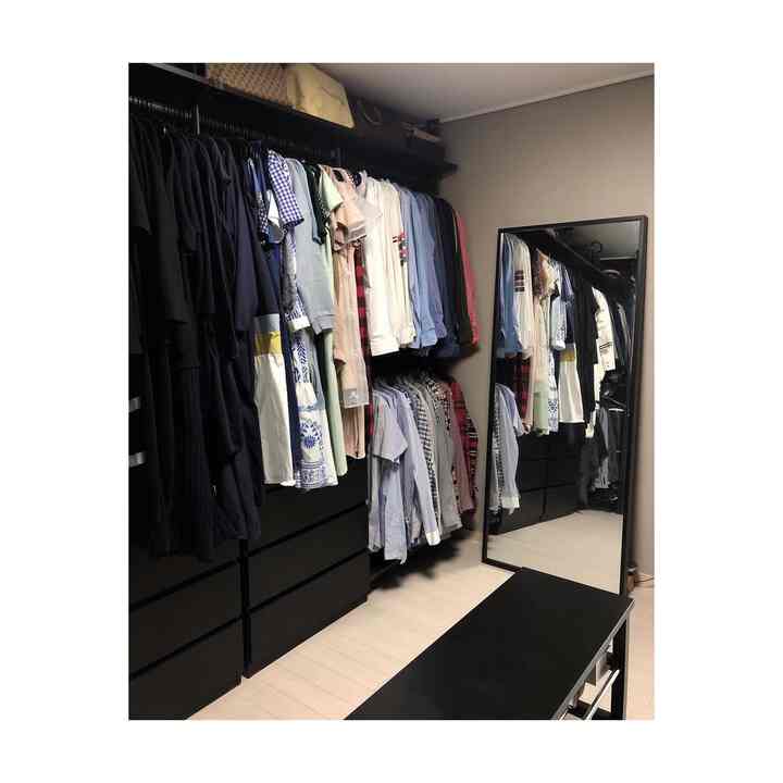 A black and navy toned walk-in closet featuring organized wardrobes and a full-length mirror with a clean atmosphere