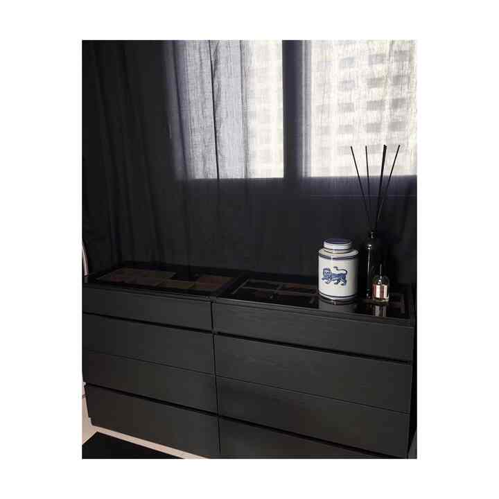All-black toned walk-in closet featuring black storage drawers and navy curtains with a sleek atmosphere