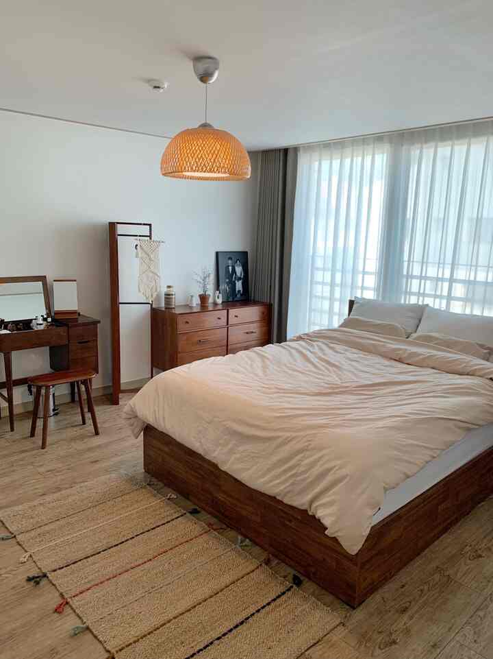 Natural tone bedroom featuring wooden furniture and beige bedding with a cozy, clean atmosphere