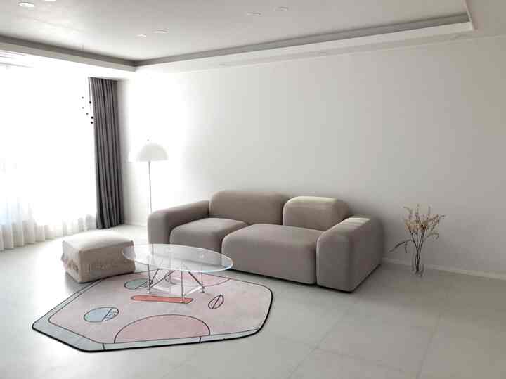 Soft beige-toned living room featuring pebble sofa, transparent coffee table, and Pantella floor lamp with a warm, natural atmosphere