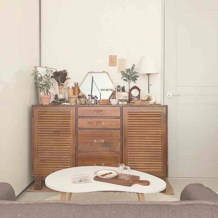 Natural tone living room with white walls and wooden storage cabinet, featuring a white table and assorted decorative accessories creating a clean atmosphere