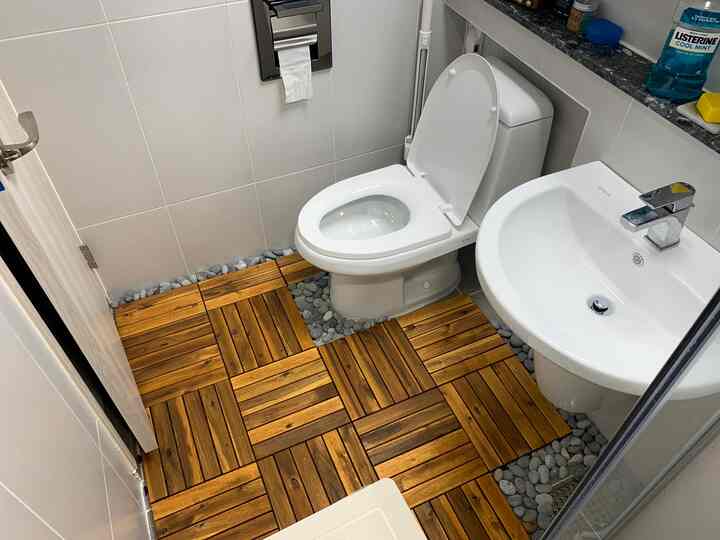 Natural wood-tone bathroom floor with pebbles in a compact bathroom and restroom, clean and modern atmosphere