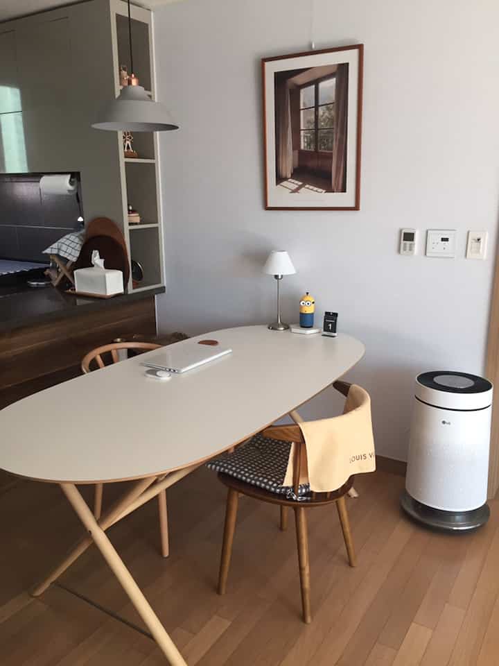 Modern kitchen space with white and wood tones featuring a 6-person dining table and wooden chairs in a clean layout