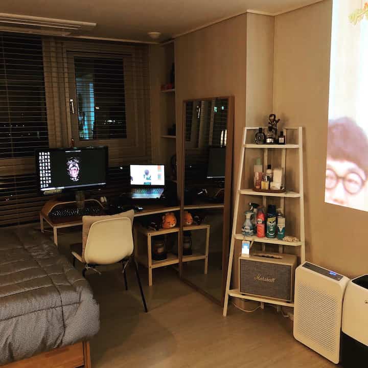 ベージュと木目調が調和する、ソファベッドとデスクが置かれたコンパクトな一人暮らし用ホームオフィスの雰囲気ある空間