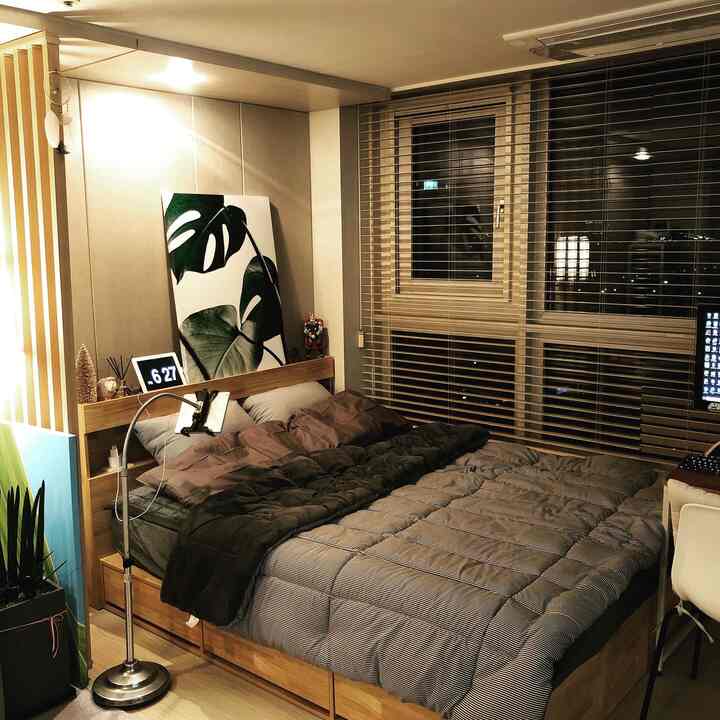 ウッドトーンとベージュの色調の寝室、大きなベッドとホームオフィスが配置された自然でモダンな雰囲気のある空間