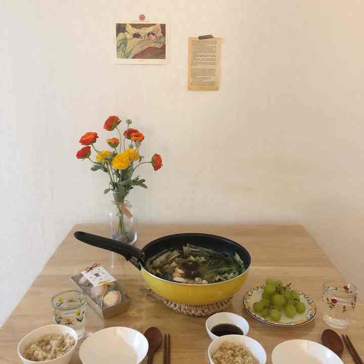 Natural-toned small dining space featuring a yellow frying pan and a vase of flowers on the table with a warm atmosphere