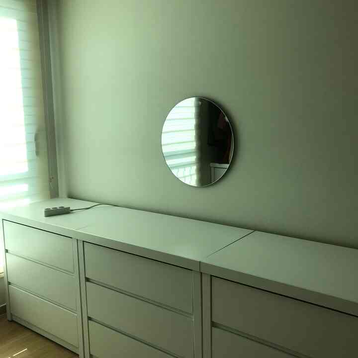 Bright and clean entrance space featuring white storage cabinets and a round mirror