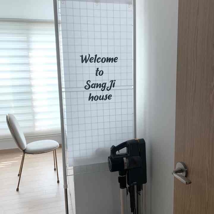 白と木目調のウォークインクローゼット入口、メッシュパーティションとゴールドベルベットチェア、コードゼロ掃除機が配置された清潔感のある空間