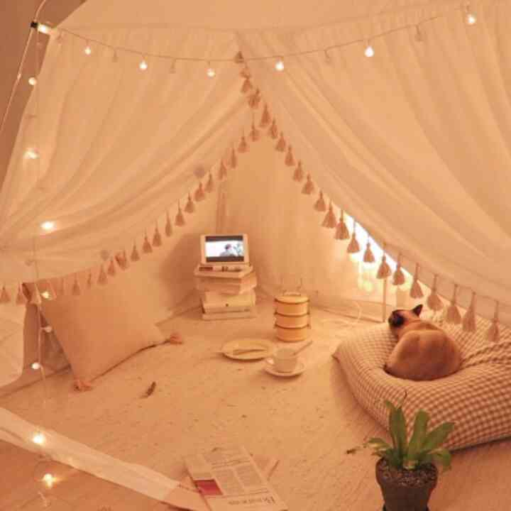 Warm beige heating tent interior with rug, bean bag, and a pet cat creating a cozy indoor space