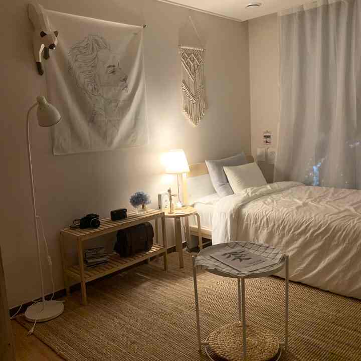 Beige-toned bedroom featuring a wooden bed, table lamp, and rug with a natural and cozy atmosphere