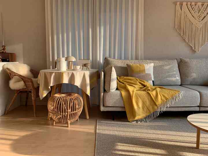 Natural living room with white curtains and wood tone furniture featuring a yellow throw blanket creating a warm atmosphere