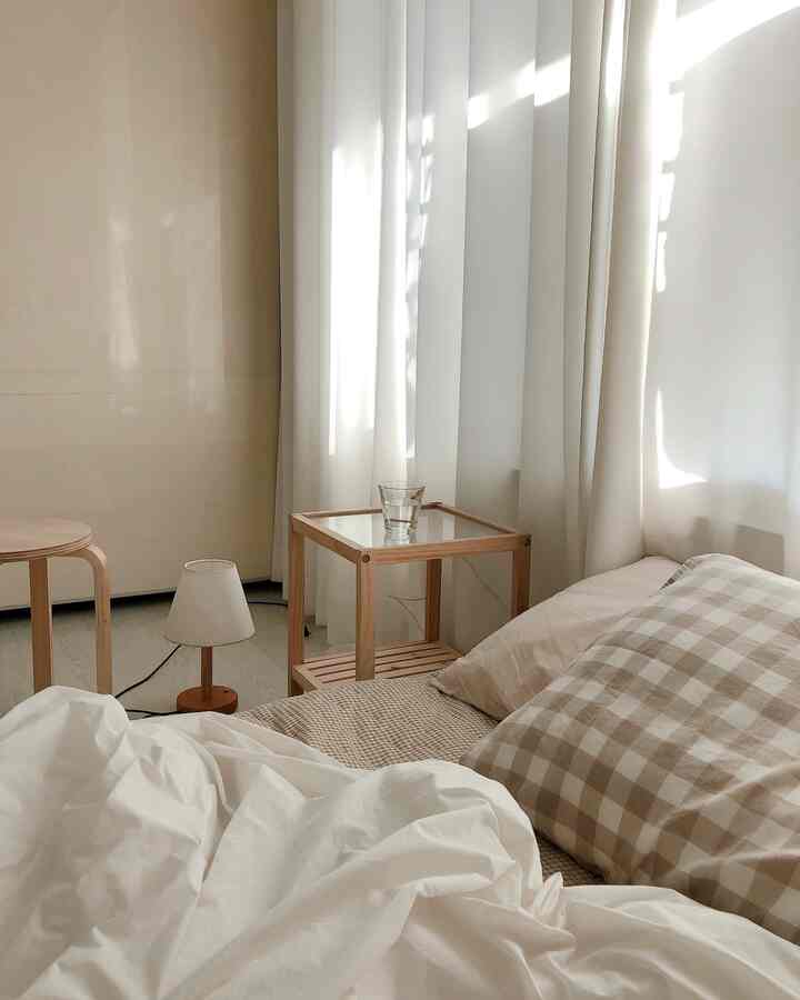 White and wood tone bedroom featuring simple, natural bedding and furniture creating a cozy atmosphere